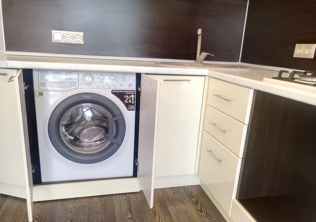 Отдельностоящая стиральная машина встроена в кухню и закрыта фасадами