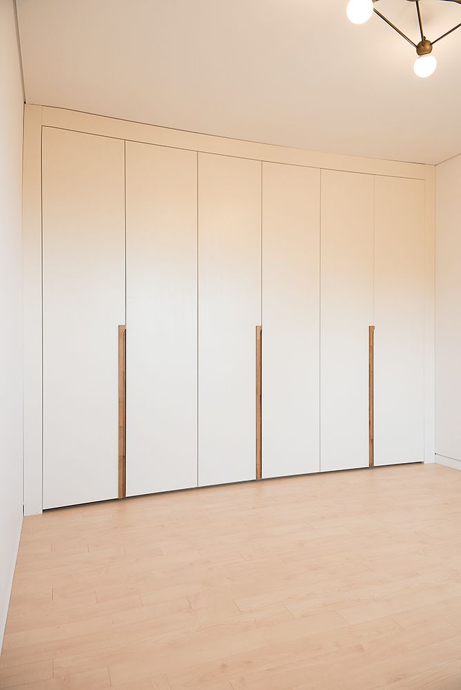 Встроенный шкаф до потолка с контрастными интегрированными ручками из дерева