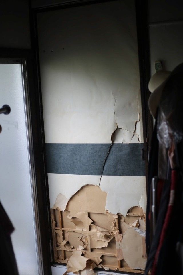 Повреждённая дверь фусума, внутри которой решетка из деревянных реек и подложка и из плотной бумаги